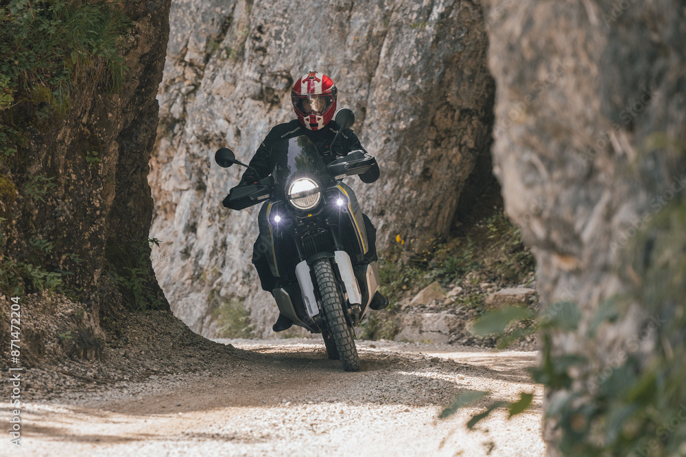 Modern adventure motorcycle on a ride on gravel surface. Motorcycling in nature or offroad, enjoying freedom. Motorbike in the woods. Frontal view