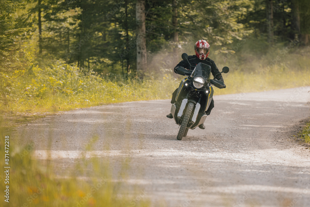 Modern adventure motorcycle on a ride on gravel surface. Motorcycling in nature or offroad, enjoying freedom. Motorbike in the woods. Making a turn Modern adventure motorcycle on a ride on gravel surface. Motorcycling in nature or offroad, enjoying freedom. Motorbike in the woods. Making a turn