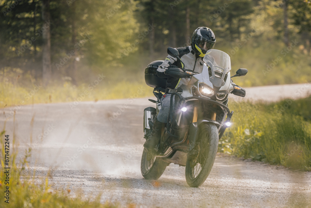 Modern adventure motorcycle on a ride on gravel surface. Motorcycling in nature or offroad, enjoying freedom. Motorbike in the woods. Making a turn