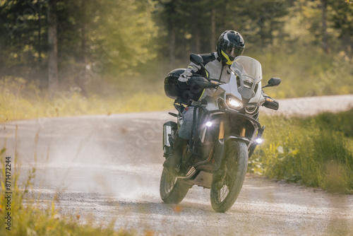 Obraz na płótnie Modern adventure motorcycle on a ride on gravel surface. Motorcycling in nature or offroad, enjoying freedom. Motorbike in the woods. Making a turn w salonie