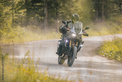 Modern adventure motorcycle on a ride on gravel surface. Motorcycling in nature or offroad, enjoying freedom. Motorbike in the woods. Making a turn photo