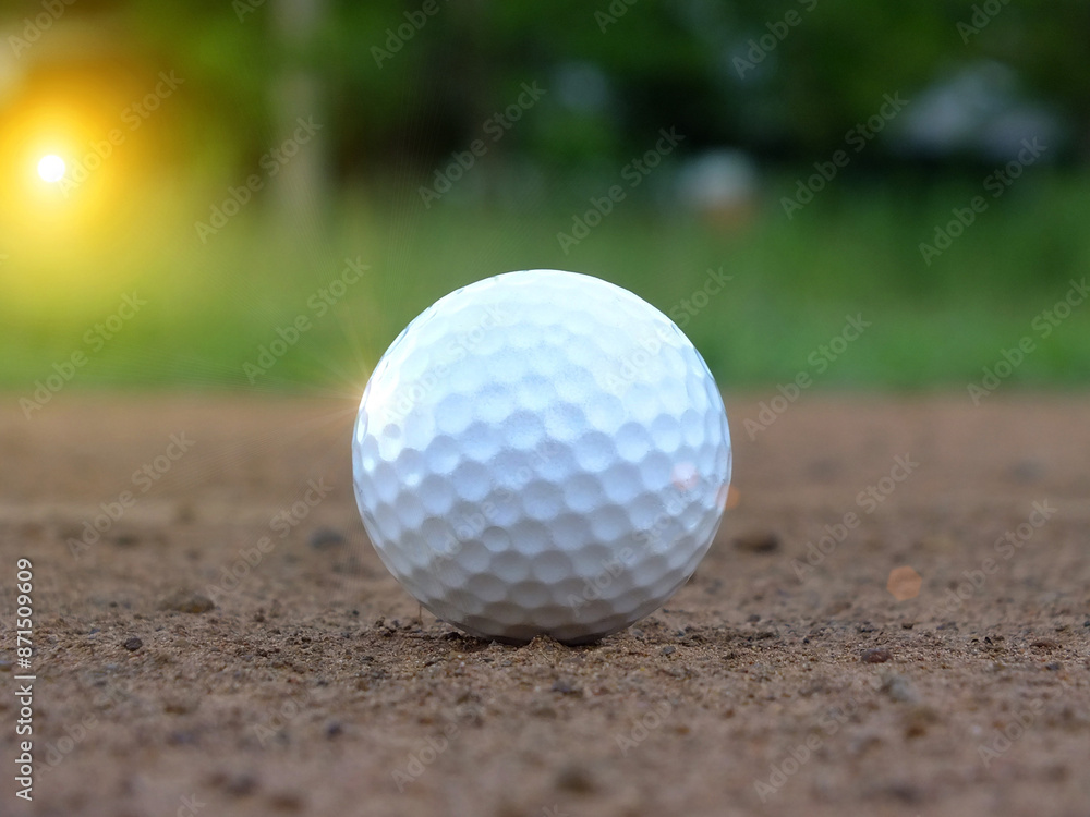 The white golf ball is outside the greens closely on the green background. And beautiful evening sky With the sun shining The white golf ball is outside the greens closely on the green background. And beautiful evening sky With the sun shining