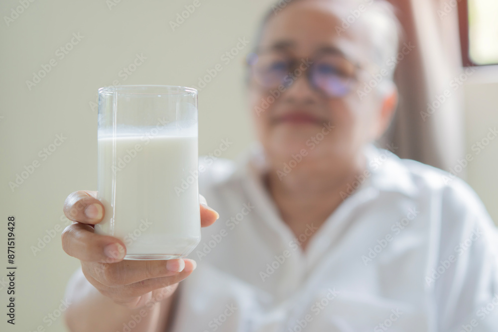 Healthy old elderly Asian grandmother holding glass of delicious fresh milk during breakfast at home. Healthy old elderly Asian grandmother holding glass of delicious fresh milk during breakfast at home.