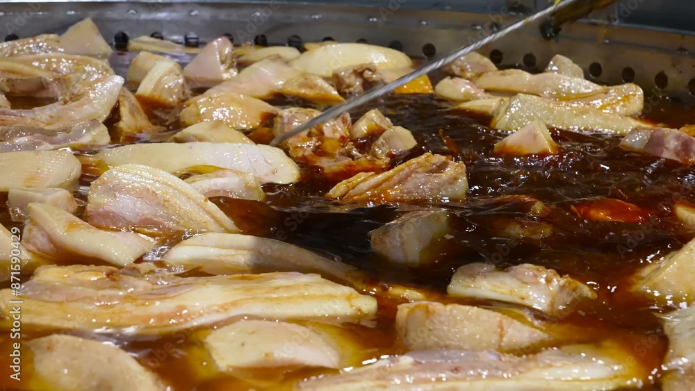 Pork ribs are being cooked on an industrial scale in large pans, simmering in a rich broth. Pork ribs are being cooked on an industrial scale in large pans, simmering in a rich broth.
