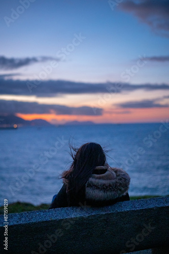 Girl looking to the sunset over the  viscay sea in the Basque Country  photo