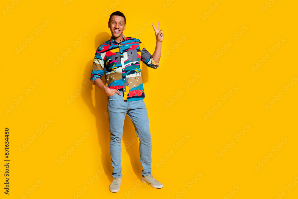 Fototapeta premium Full size photo of handsome young guy show v-sign wear trendy colorful outfit isolated on yellow color background