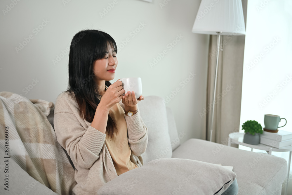 Portrait of attractive Asian woman enjoying coffee while resting on couch in the morning Portrait of attractive Asian woman enjoying coffee while resting on couch in the morning