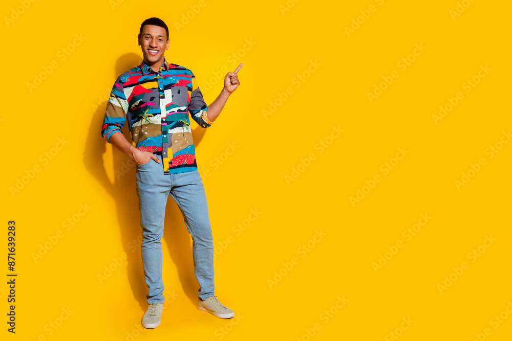 Full length photo of nice young male point empty space dressed stylish colorful garment isolated on yellow color background Full length photo of nice young male point empty space dressed stylish colorful garment isolated on yellow color background