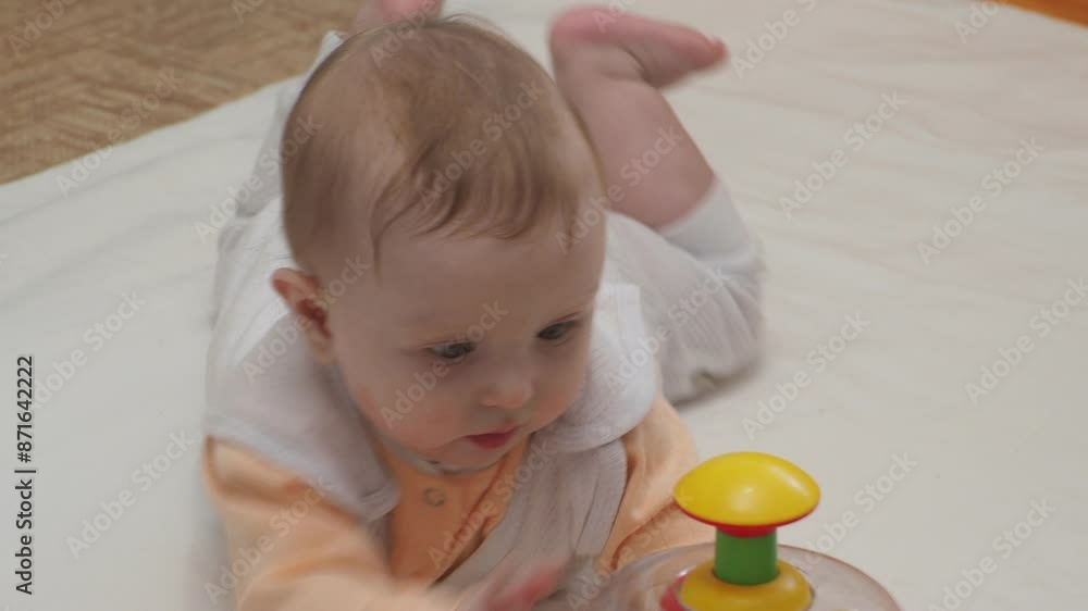 Adorable happy blonde infant baby playing with kids toys at home while sitting on carpet floor in living room. Portrait of smiling cute child toddler using colorful toys, copy space Adorable happy blonde infant baby playing with kids toys at home while sitting on carpet floor in living room. Portrait of smiling cute child toddler using colorful toys, copy space