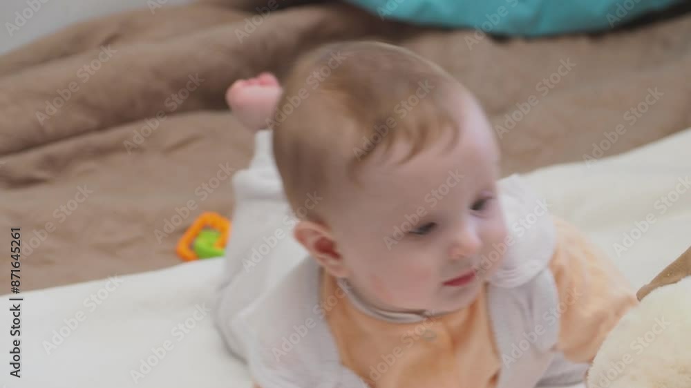 Adorable happy blonde infant baby playing with kids toys at home while sitting on carpet floor in living room. Portrait of smiling cute child toddler using colorful toys Adorable happy blonde infant baby playing with kids toys at home while sitting on carpet floor in living room. Portrait of smiling cute child toddler using colorful toys