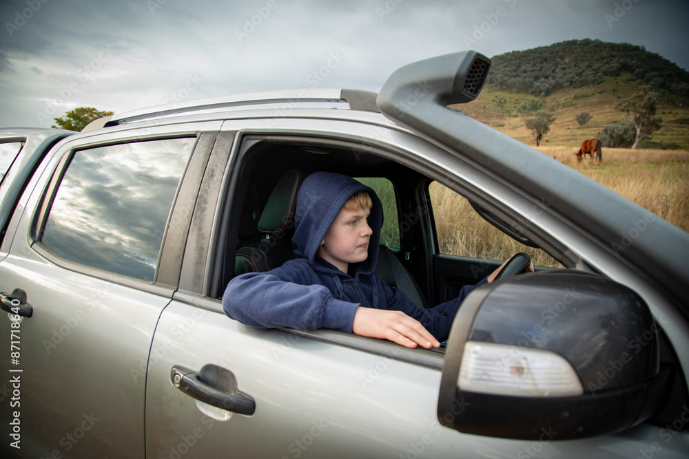 Teen boy driving ute on farm Teen boy driving ute on farm