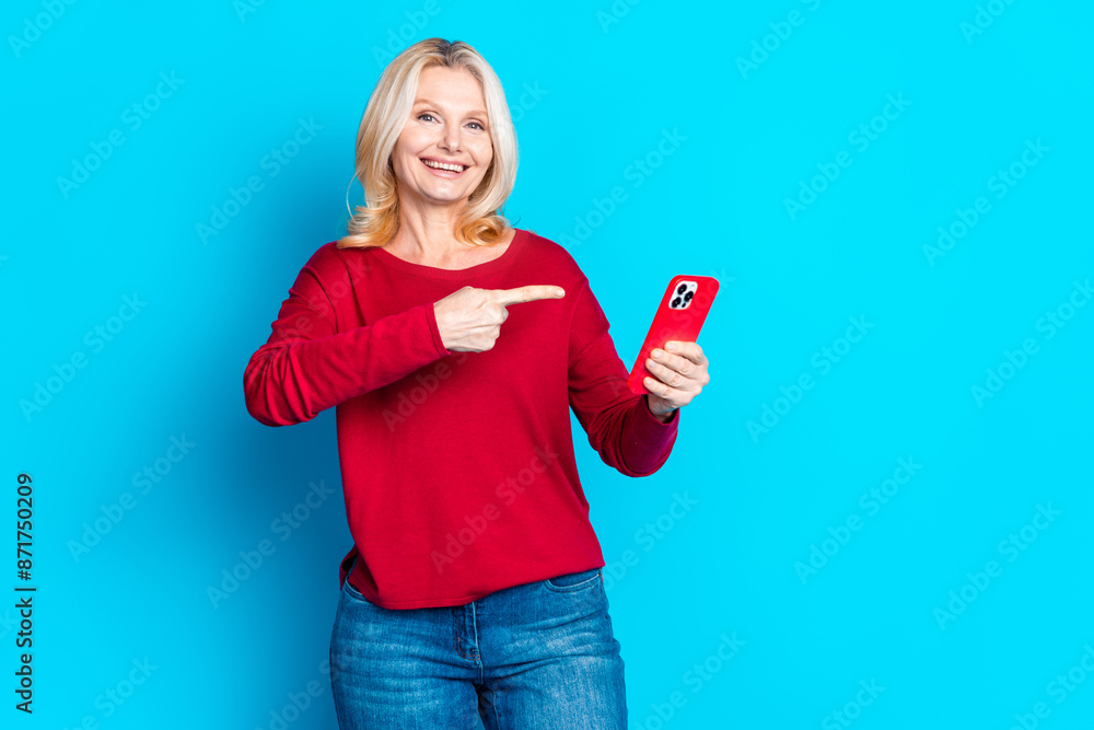 Photo portrait of attractive retired woman hold point device dressed stylish red clothes isolated on blue color background Photo portrait of attractive retired woman hold point device dressed stylish red clothes isolated on blue color background