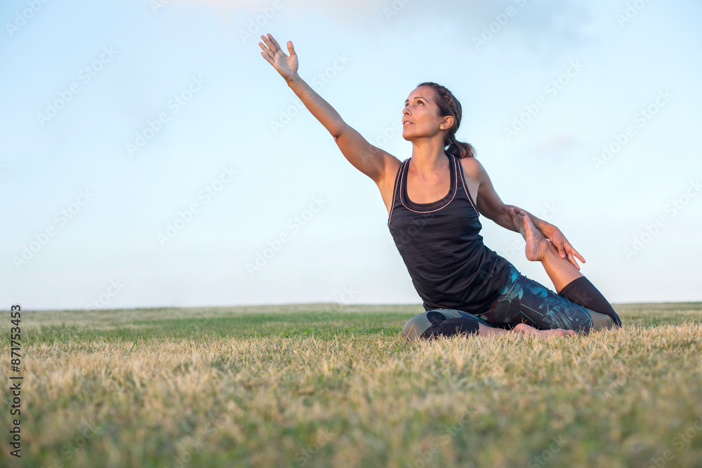 Woman practicing yoga pose on a grassy field, reaching upward... Woman practicing yoga pose on a grassy field, reaching upward...