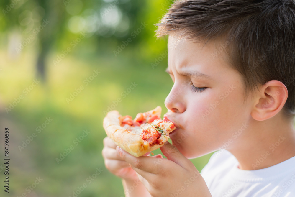 Cute child eating pizza in nature in summer Cute child eating pizza in nature in summer