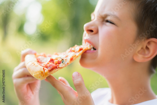 Cute child eating pizza in nature in summer