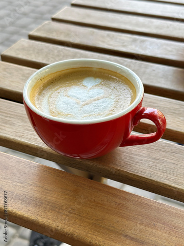 Red coffee cup sitting on wooden table in cafe