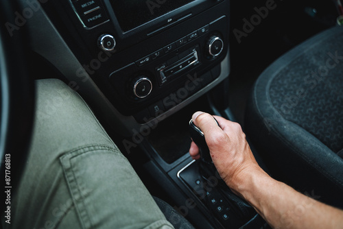 A person is carefully adjusting a gear in a luxurious car, focusing on precise automotive design. The scene captures the intricacy and attention to detail in the interior of the vehicle © Aleksey