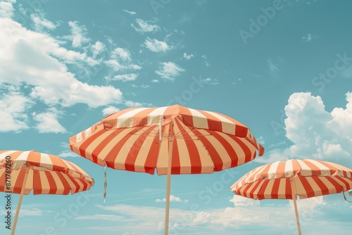 Fototapeta Naklejka Na Ścianę i Meble -  Three umbrellas are set up on a beach, with the sky above them