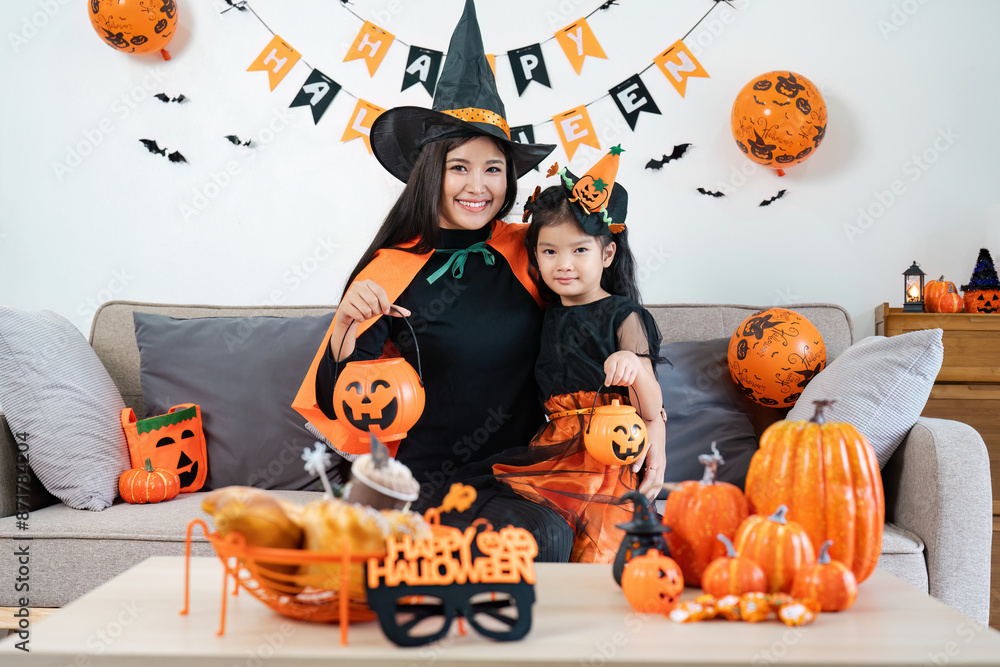 Fototapeta premium Mother and Daughter Celebrating Halloween at Home with Costumes, Pumpkins, and Festive Decorations