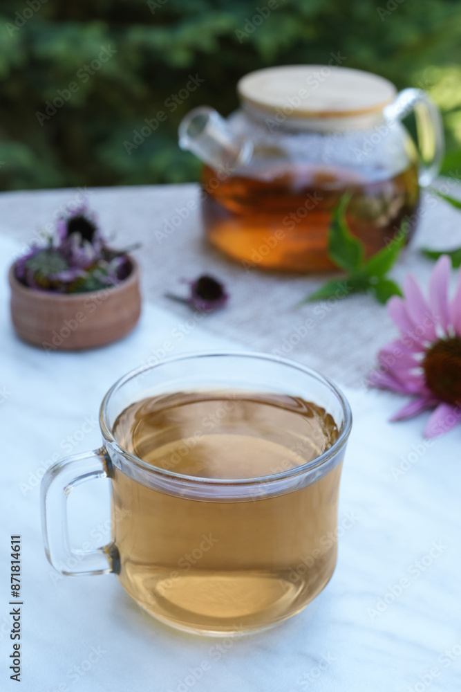 Herbal tea in a glass cup, teapot, fresh and dried flowers of echinacea on a marble background. Side view. Herbal tea in a glass cup, teapot, fresh and dried flowers of echinacea on a marble background. Side view.