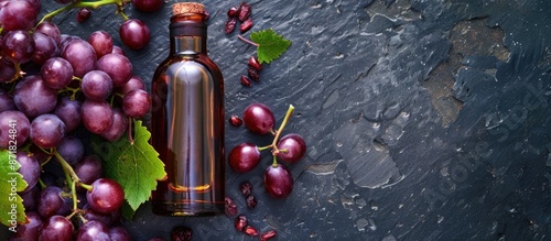 Top view of a bottle of grape seed oil placed beside fresh grapes, with copy space image included. photo