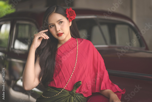 Beautiful portrait of an Asian female. A pretty woman wearing a red sash and green loincloth a traditional Thai dress costume. Asian tourists dress to blend in ancient Thai culture.