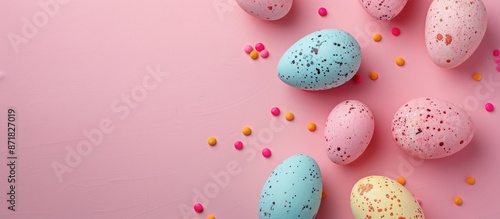 Colorful Easter eggs on textured pink paper background with ample copy space image for text, captured from a top view in a flat lay style with a close-up shot.