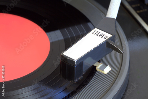 Old vintage stereo record player with 7 inch vinyl record with red label on the mat top view close-up