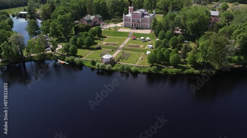 Aerial view of the small town of Birini Castle, located in a green park. The parish is surrounded by well-maintained paths, trees and open grass. Residential buildings and a lake photo