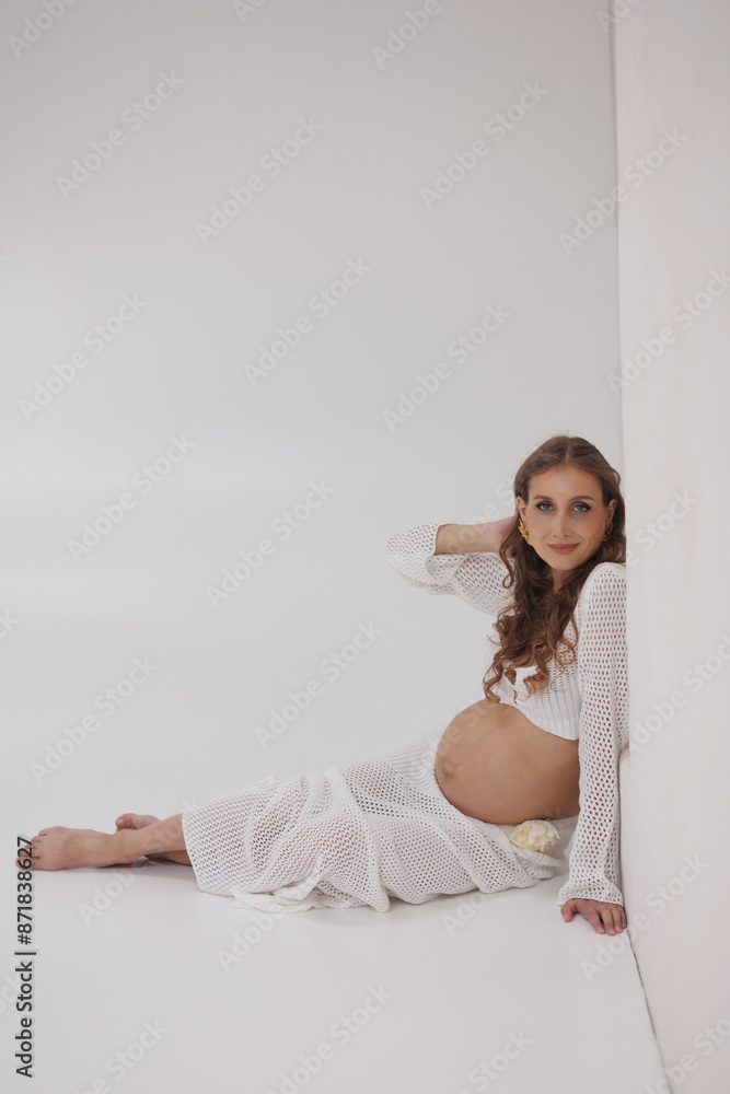 Beautiful pregnant woman in white separate dress. Big pregnant belly. Pretty woman waiting child. Light play on woman's body and face Beautiful pregnant woman in white separate dress. Big pregnant belly. Pretty woman waiting child. Light play on woman's body and face