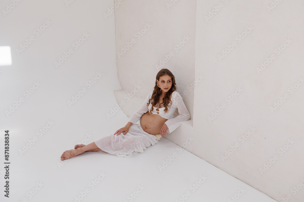 Beautiful pregnant woman in white separate dress. Big pregnant belly. Pretty woman waiting child. Light play on woman's body and face Beautiful pregnant woman in white separate dress. Big pregnant belly. Pretty woman waiting child. Light play on woman's body and face