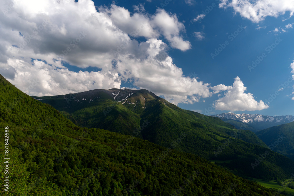 Mountain range with lush green slopes and blue sky Mountain range with lush green slopes and blue sky
