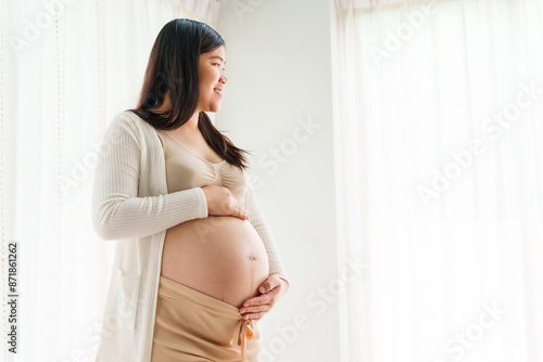 An Asian young pregnant wife relaxes at home, her hand gently resting on her belly, filled with love and anticipation as she embraces the journey of impending motherhood. Free Download An Asian young pregnant wife relaxes at home, her hand gently resting on her belly, filled with love and anticipation as she embraces the journey of impending motherhood. - GFXLoad