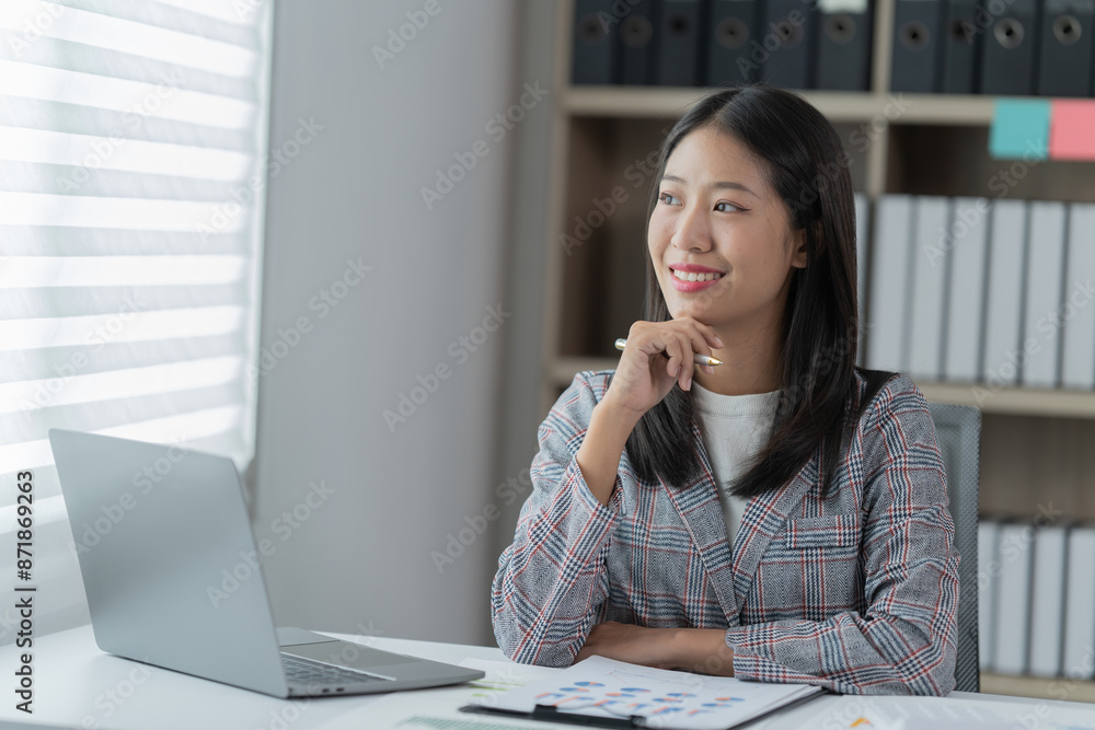 Sharing good business news. Attractive young businesswoman talking on the mobile phone and smiling while sitting at her working place in office and looking at laptop PC. Sharing good business news. Attractive young businesswoman talking on the mobile phone and smiling while sitting at her working place in office and looking at laptop PC.