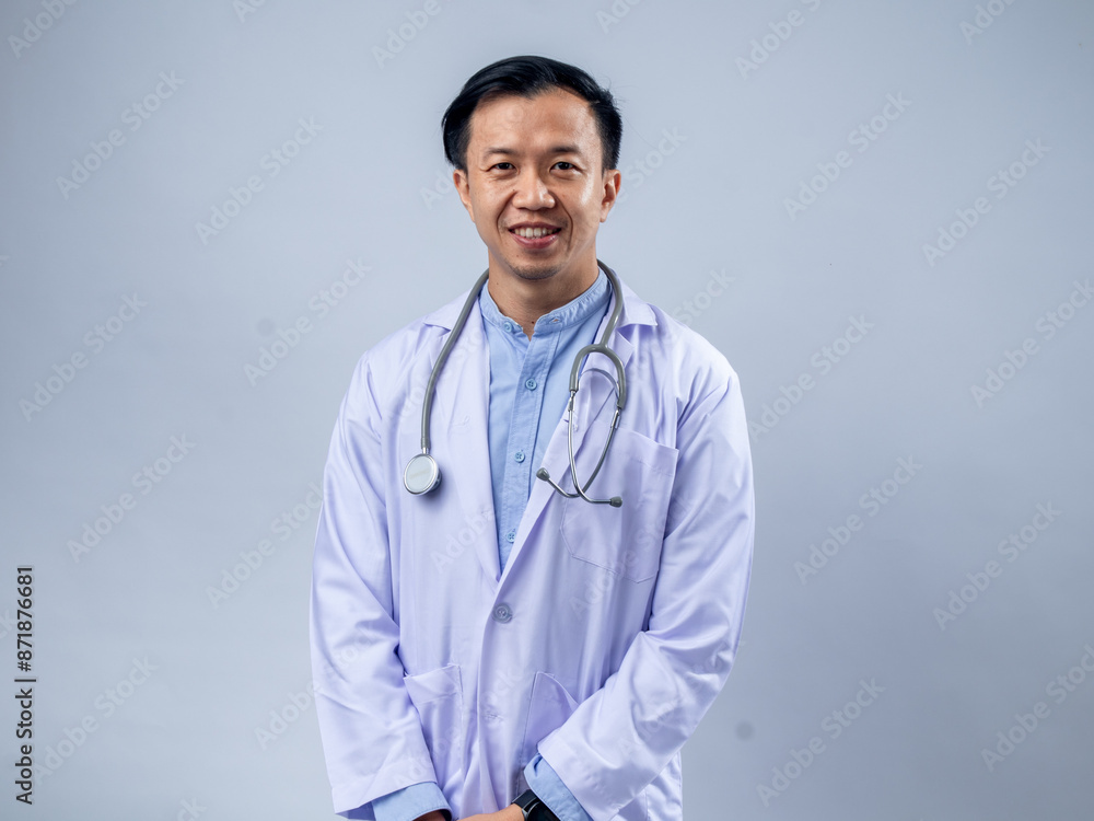 Asian male doctor with a stethoscope around his neck, wearing a white lab coat and light blue shirt, hands in pockets, smiling confidently. Plain background, ideal for healthcare and medical Asian male doctor with a stethoscope around his neck, wearing a white lab coat and light blue shirt, hands in pockets, smiling confidently. Plain background, ideal for healthcare and medical