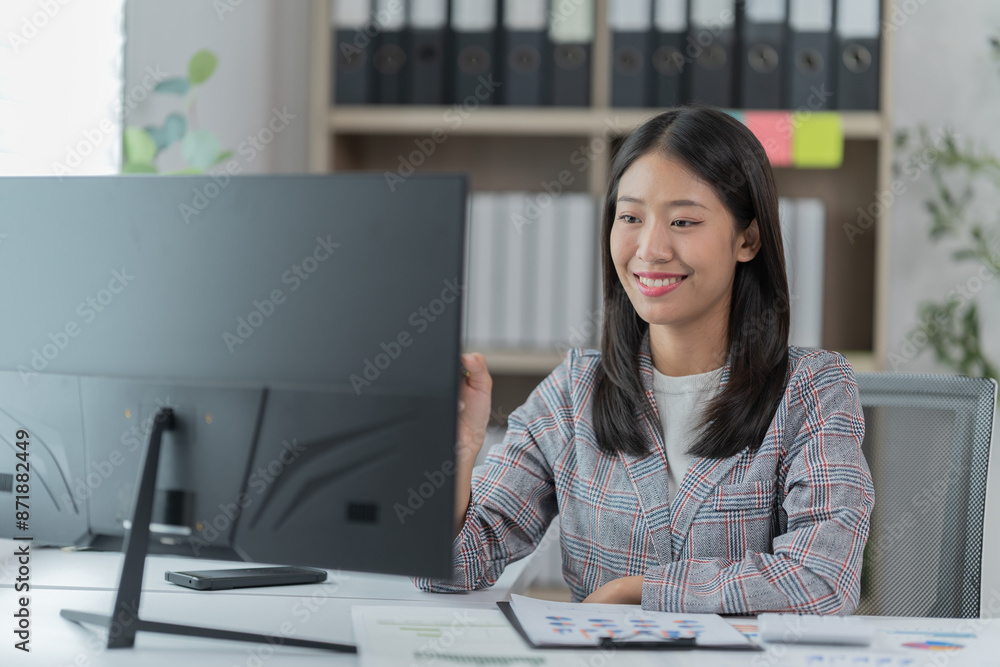 Sharing good business news. Attractive young businesswoman talking on the mobile phone and smiling while sitting at her working place in office and looking at laptop PC. Sharing good business news. Attractive young businesswoman talking on the mobile phone and smiling while sitting at her working place in office and looking at laptop PC.
