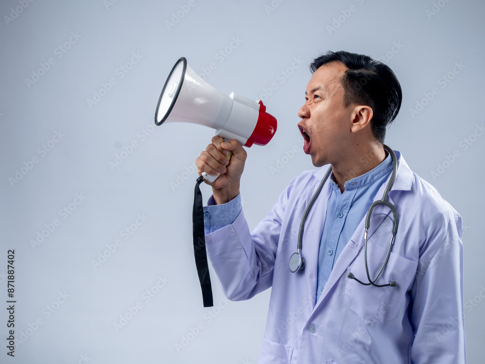 Asian male doctor in a white coat holding a megaphone and speaking enthusiastically. The plain background emphasizes the focus on the doctor's energetic announcement and the stethoscope Asian male doctor in a white coat holding a megaphone and speaking enthusiastically. The plain background emphasizes the focus on the doctor's energetic announcement and the stethoscope