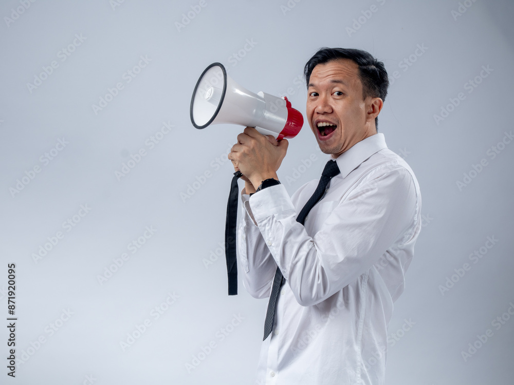 Asian businessman in white shirt and black tie enthusiastically holding a megaphone, speaking or announcing with a joyful expression, standing against a plain light background Asian businessman in white shirt and black tie enthusiastically holding a megaphone, speaking or announcing with a joyful expression, standing against a plain light background