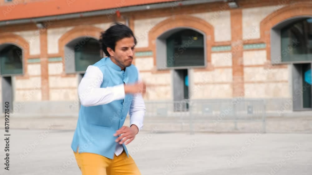 Young indian man dancing in the street wearing colorful clothes Young indian man dancing in the street wearing colorful clothes