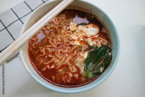 a Bowl of spicy noodle soup or mie kuah or boiled noodles with boiled egg and green mustard. Looks so warm and delicious. Indomie rebus. photo