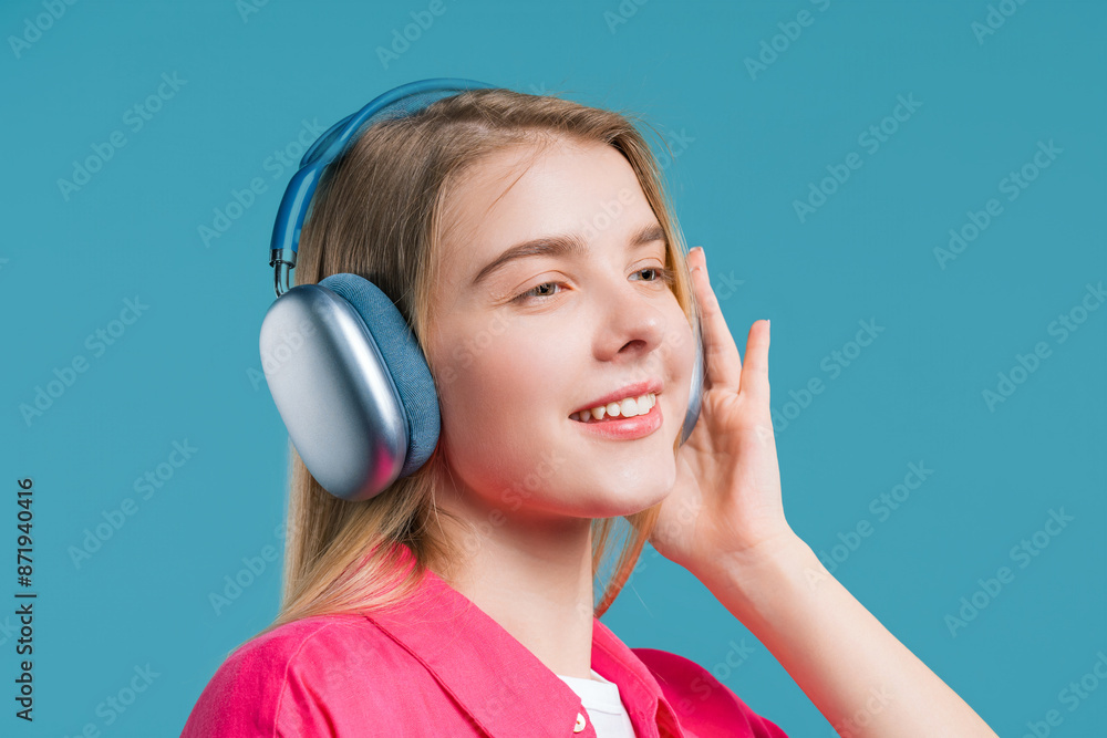 Naklejka premium Cute woman listening streaming music, enjoying dance with headphones on blue