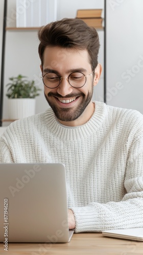 A man sits at a table in his home office, working on a laptop computer.