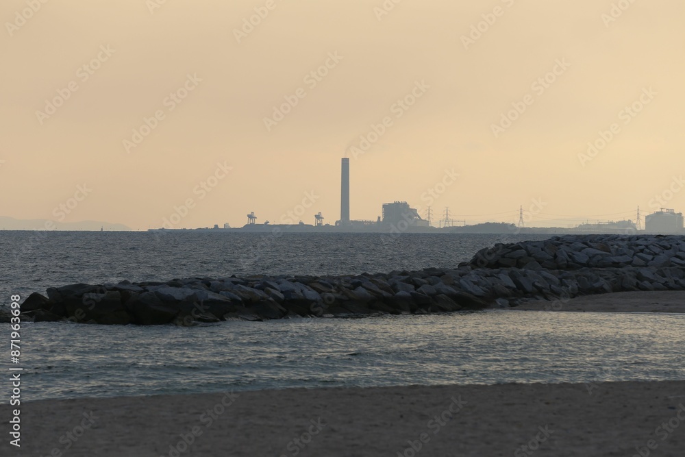 Fototapeta premium The coastline in the evening after sunset with an oil refinery behind,.