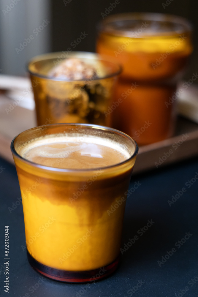Close-up of dirty coffee in yellow glass, cup of iced coffee on table Close-up of dirty coffee in yellow glass, cup of iced coffee on table