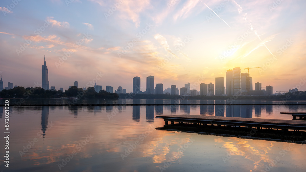 Fototapeta premium Urban Skyline at Sunset Over Tranquil Lake