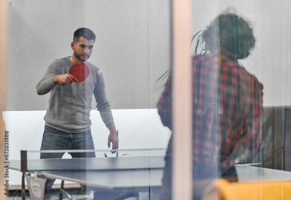 Fototapeta premium Business colleagues take a break from work to enjoy a game of table tennis, fostering teamwork and camaraderie in the workplace
