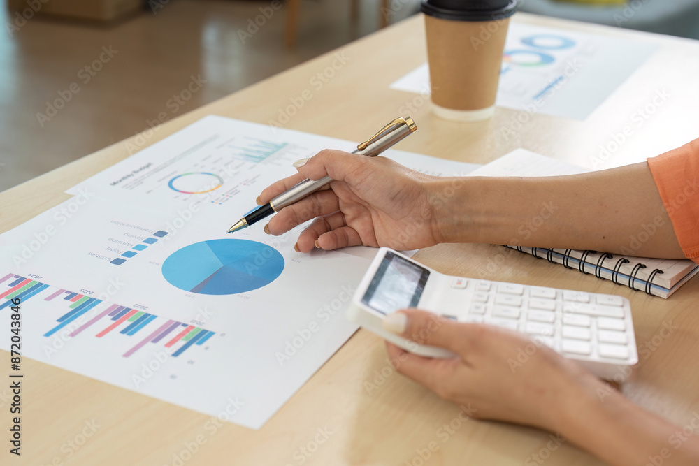 Business Person Analyzing Financial Data with Charts and Calculator in Office Setting Business Person Analyzing Financial Data with Charts and Calculator in Office Setting
