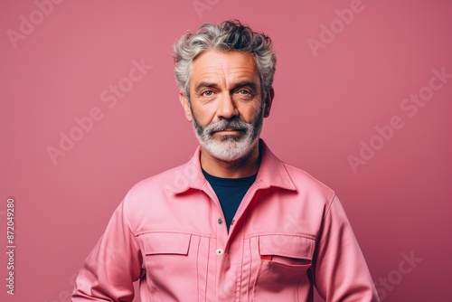 A man in a pink shirt is standing in front of a pink background