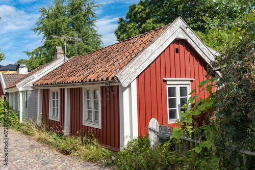 Fototapeta Naklejka Na Ścianę i Meble -  Kalmar a beautiful town in the south of Sweden. Travel touristic Landmark. Traditional little red wooden houses. Beautiful small cozy house with clay tile roof. Plants and roses decorates home entre. 