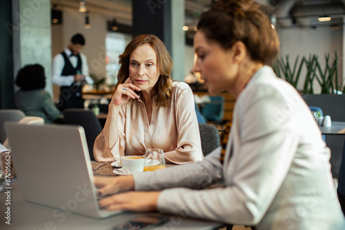 Diverse businesswomen having meeting in hotel restaurant photo